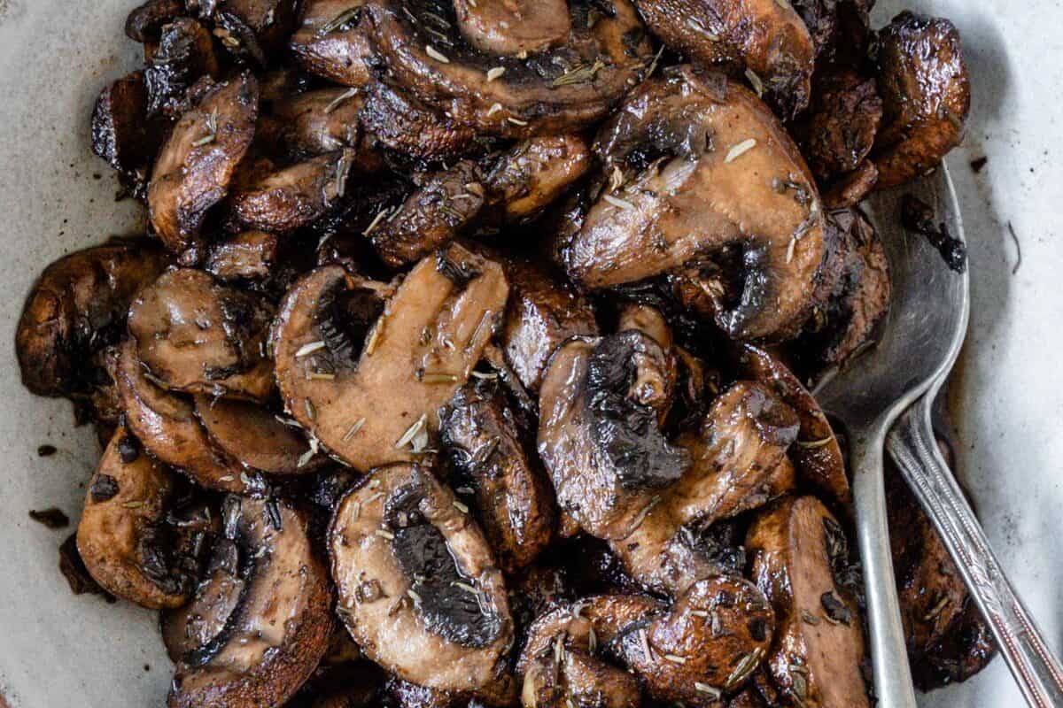 completed simple roasted mushrooms on a white plate against a white background
