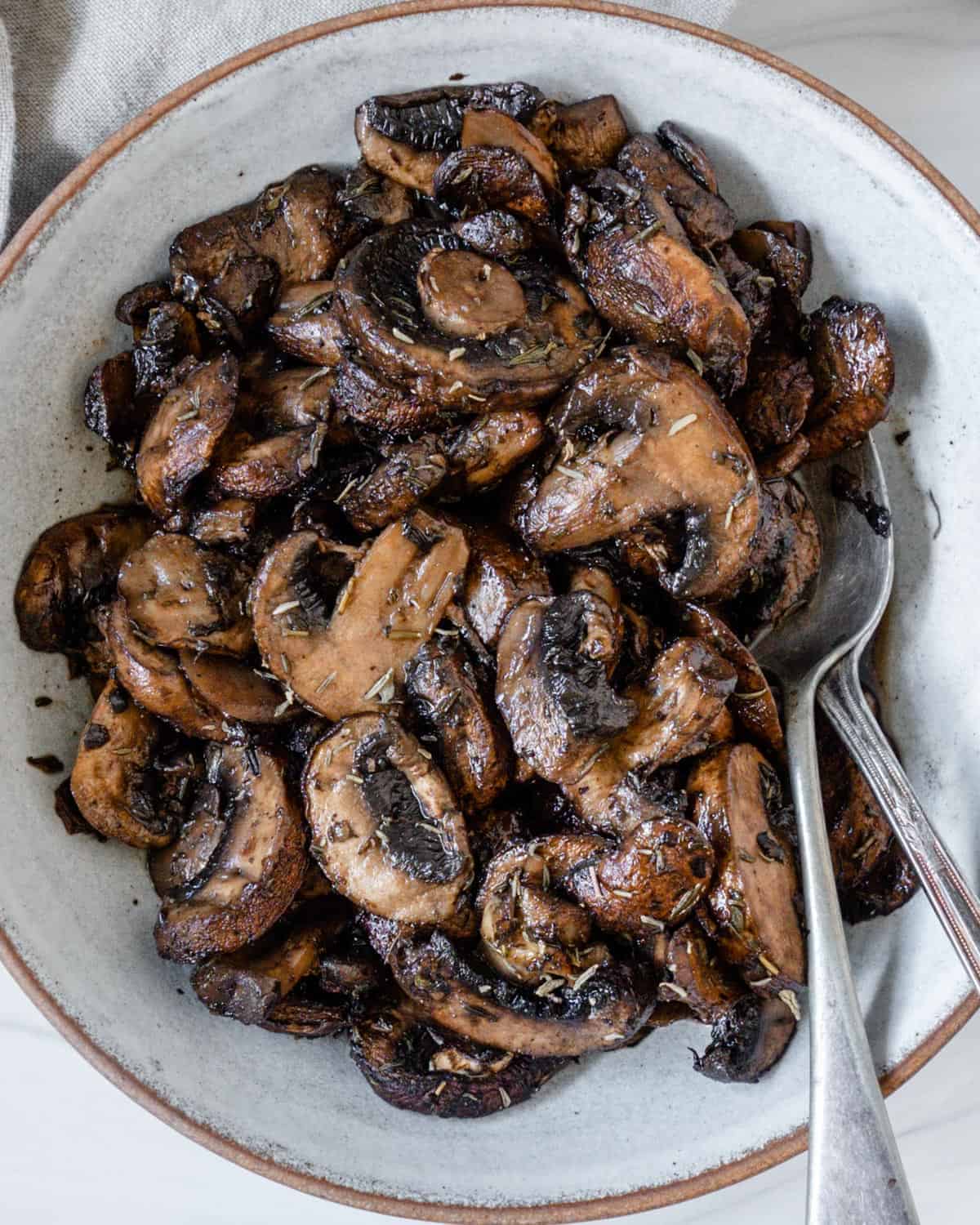 completed simple roasted mushrooms on a white plate against a white background