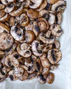 seasoned mushrooms on baking tray with parchment paper prior to being roasted 