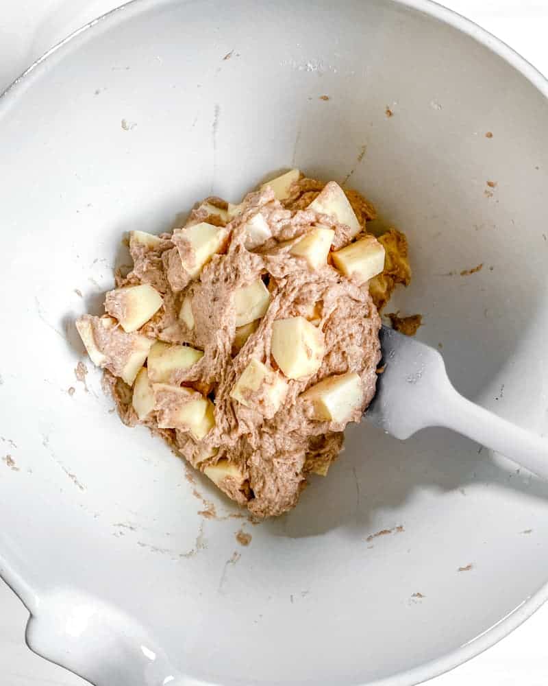 process of mixing apples to apple cake mixture in bowl
