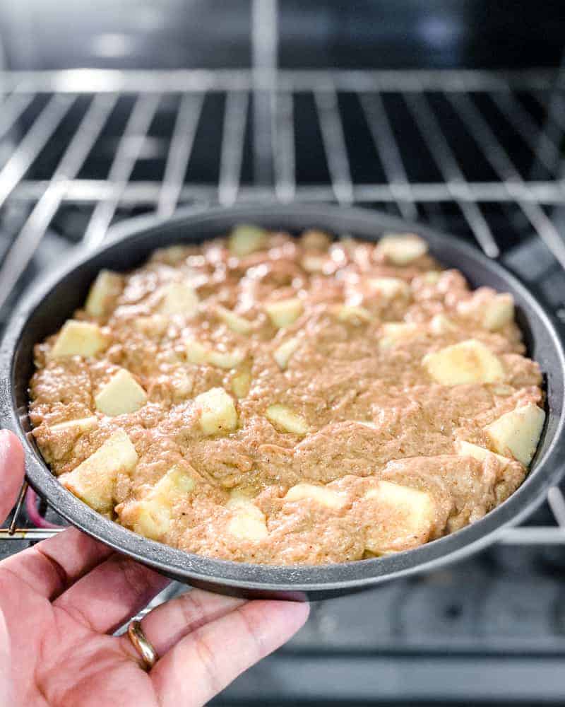 raw apple cake being put into the oven
