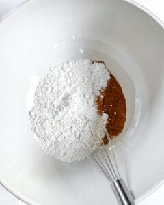 the process of addition of dry ingredients into wet ingredients in white bowl