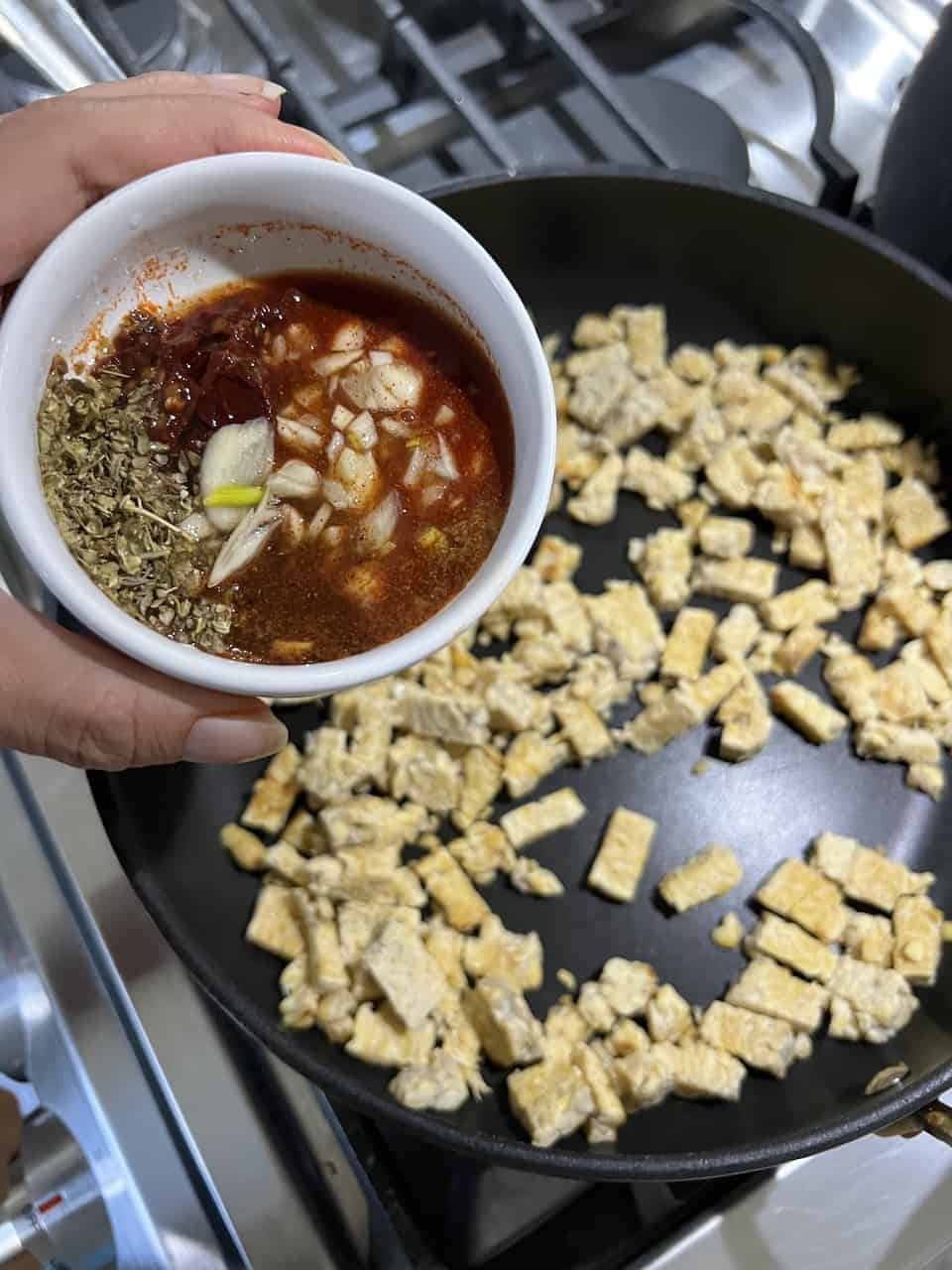 process of adding flavoring to tempeh on a black griddle