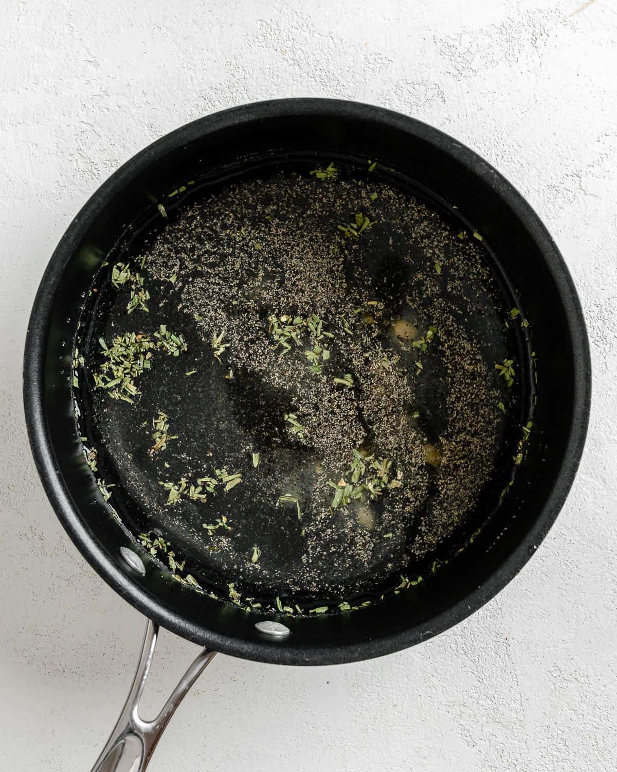 process shot of mixing spices in a black pan against a white background