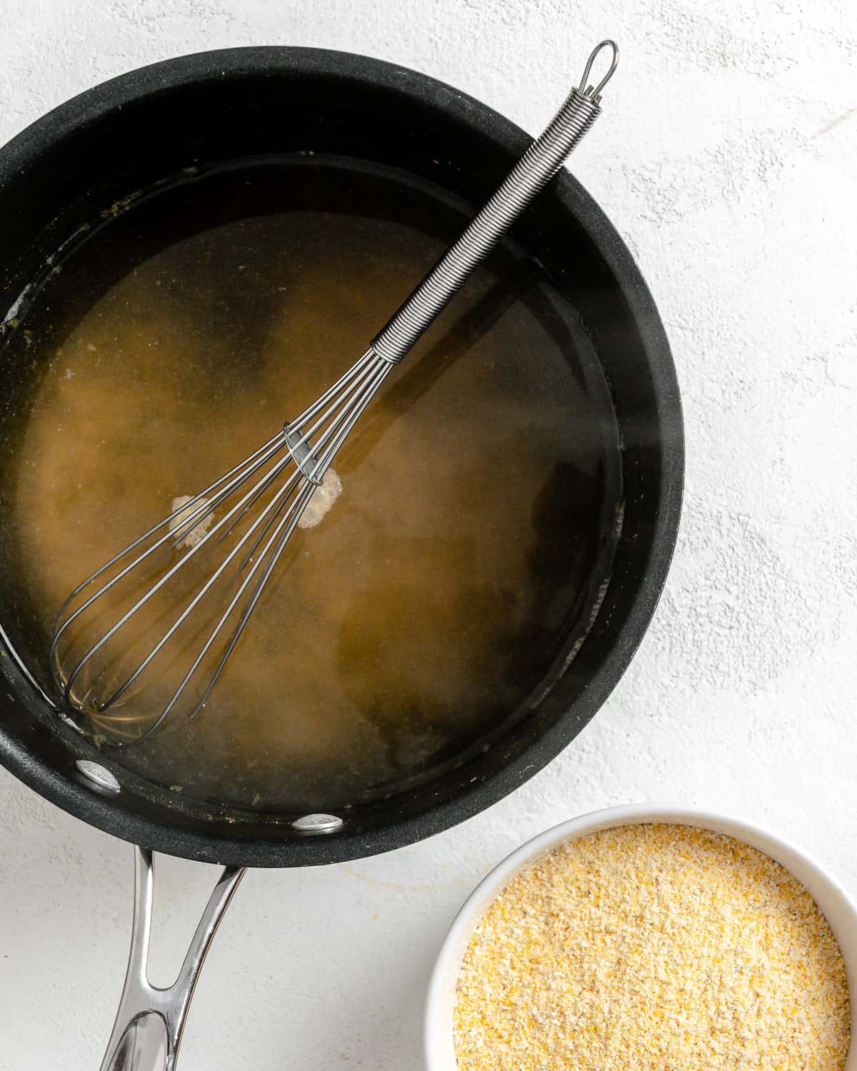 process shot of mixing cornmeal in pot against white surface