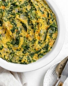 completed Garlicky Spinach and Pepper Polenta Pie in a white backing dish against a white surface