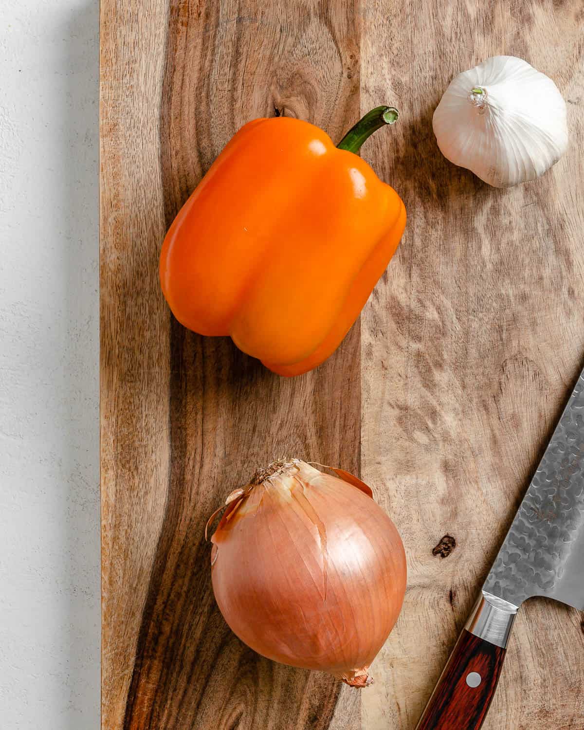 whole garlic, pepper, and onion on a cutting board
