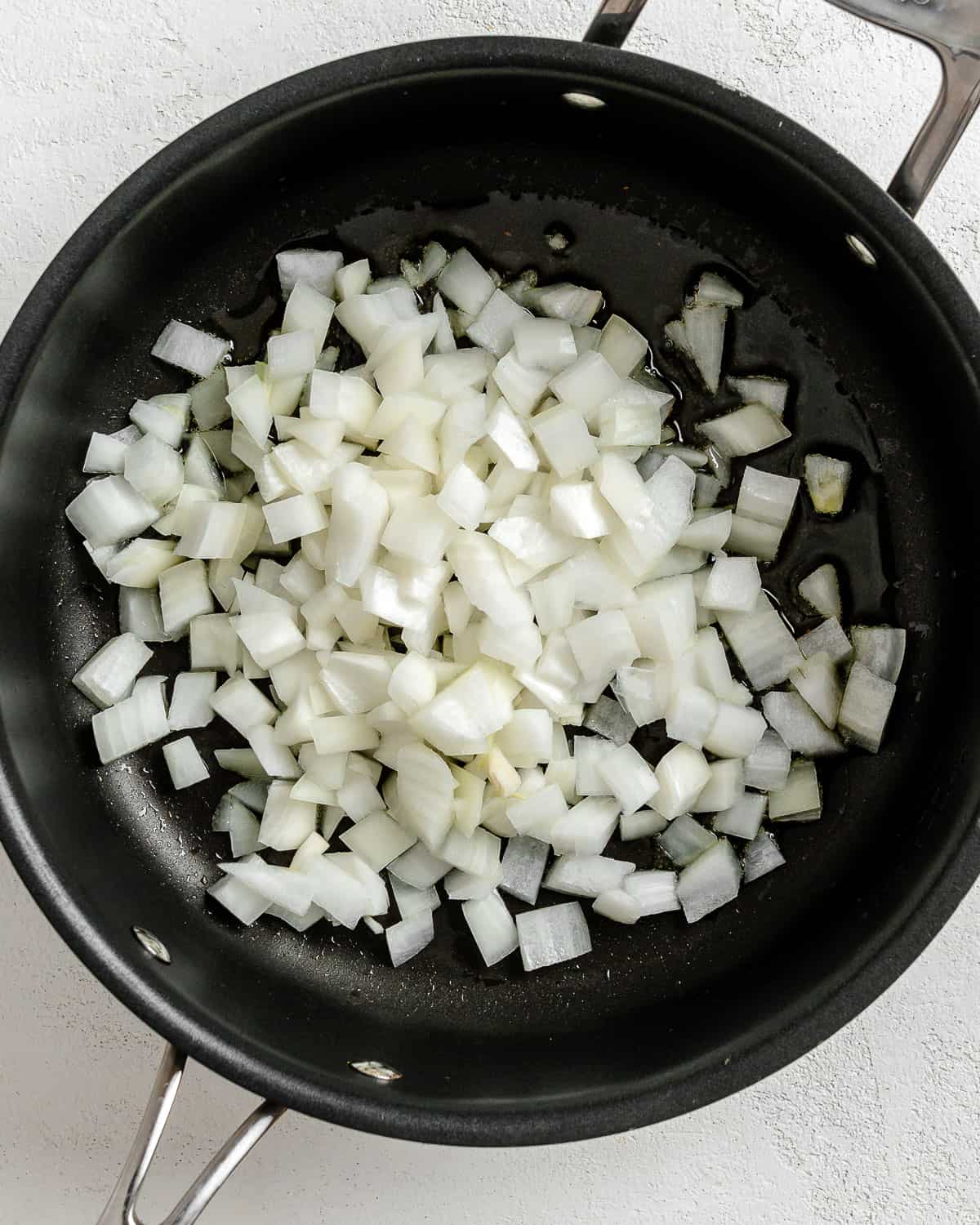process of adding onions in a black pan