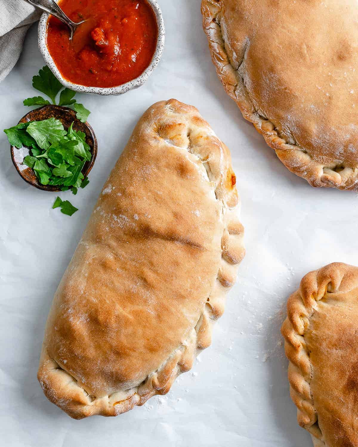 three completed completed Marinara Calzones against white surface