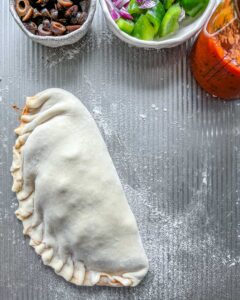 one un-baked calzone on a gray surface