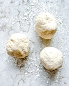 three balls of dough against white surface