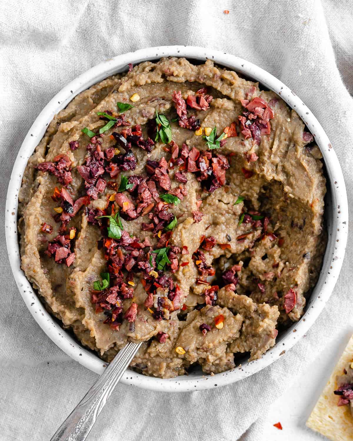Completed Spicy Lentil Kalamata Dip in a white bowl against a white background.