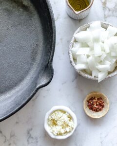 ingredients for Spicy Lentil Kalamata Dip measured out against a white surface alonside pan