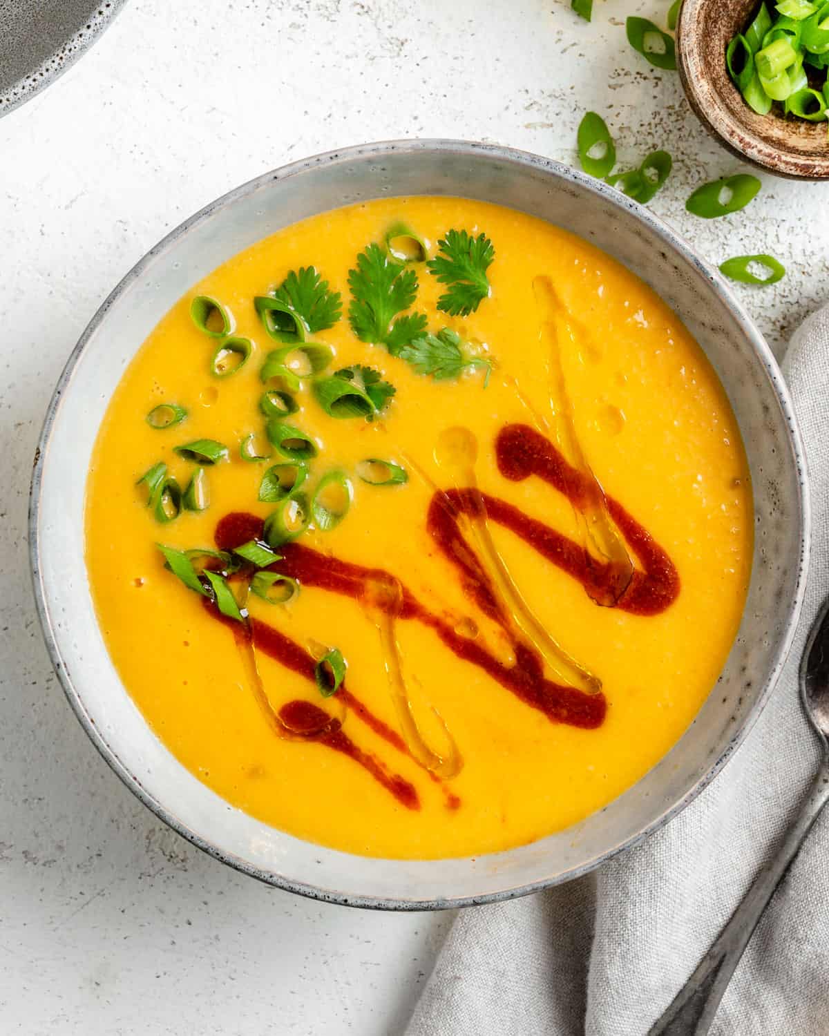 ready Thai butternut squash soup in a white bowl against a white background