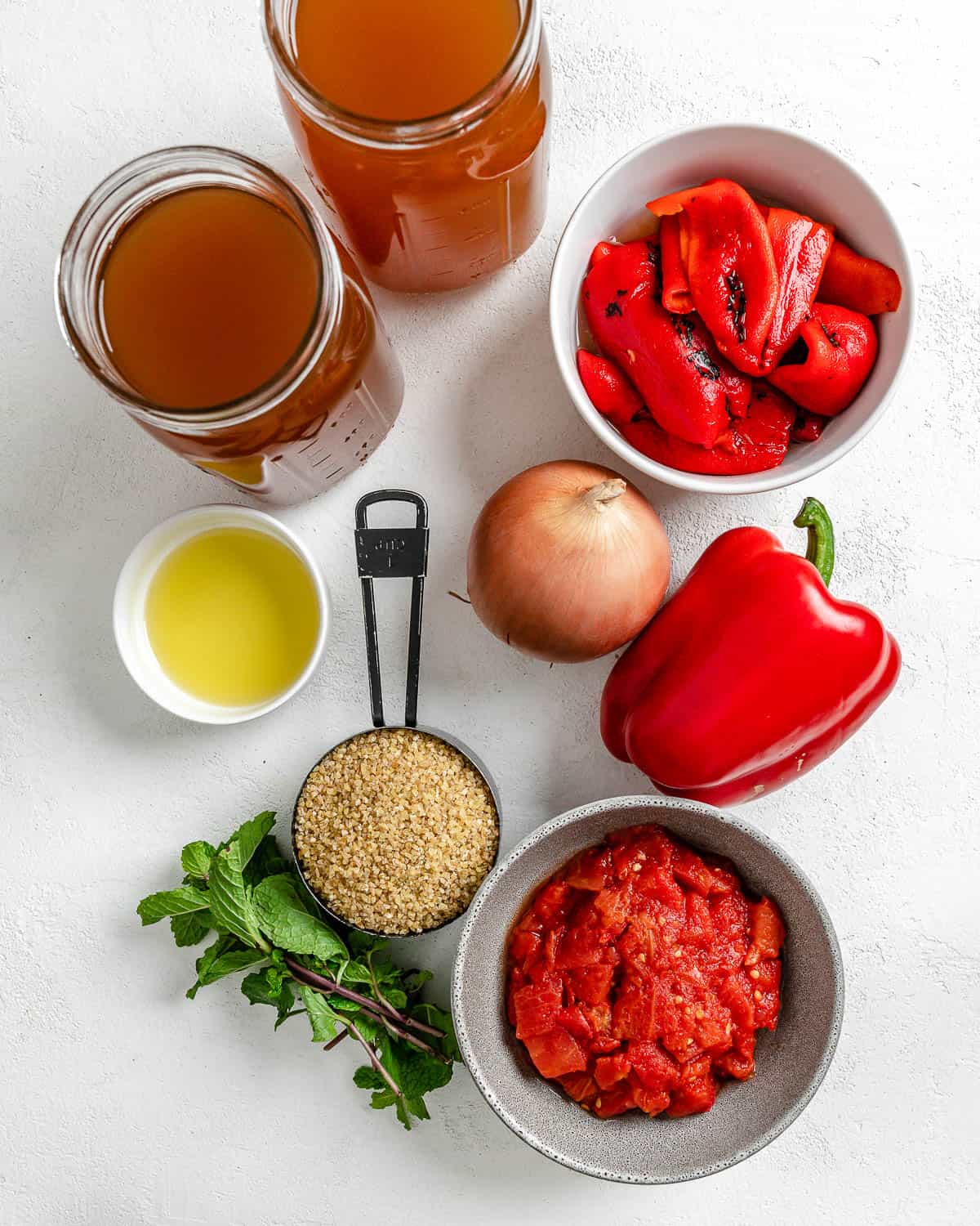 ingredients for Turkish Tomato, Bulgur, and Red Pepper Soup against a white surface