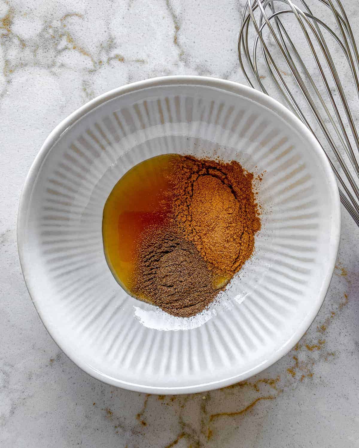 ingredients for cinnamon almonds added to white bowl against white surface