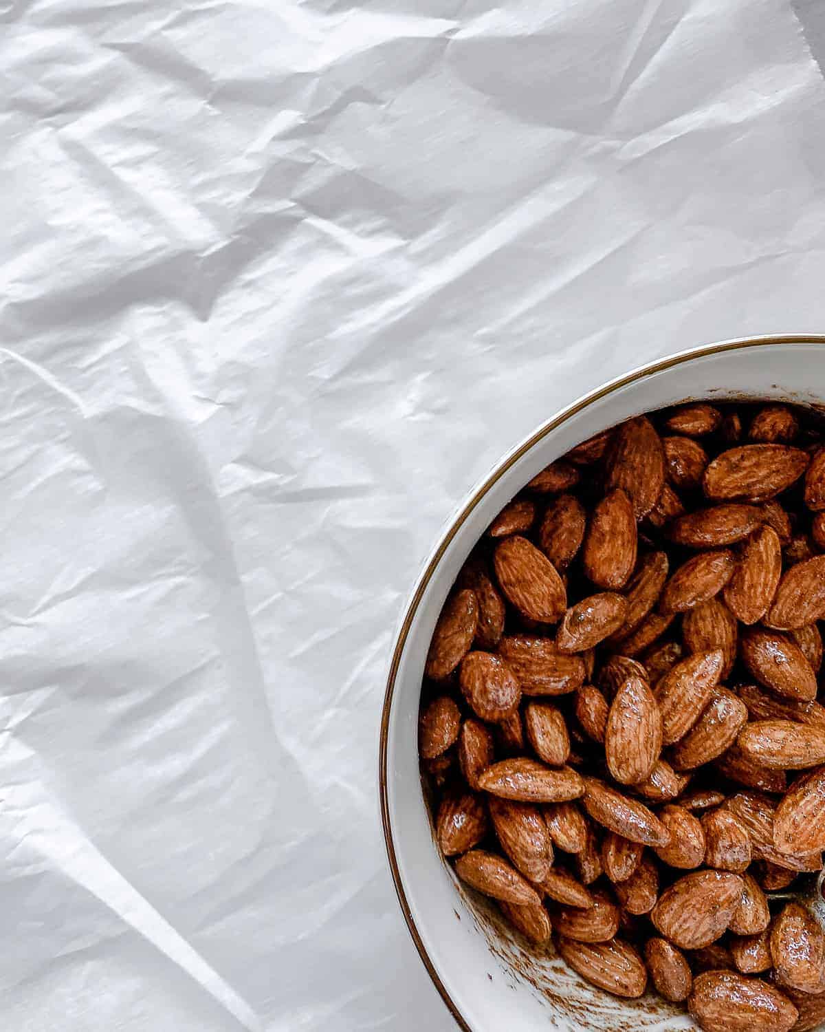 completed cinnamon almonds in a white bowl against a white surface