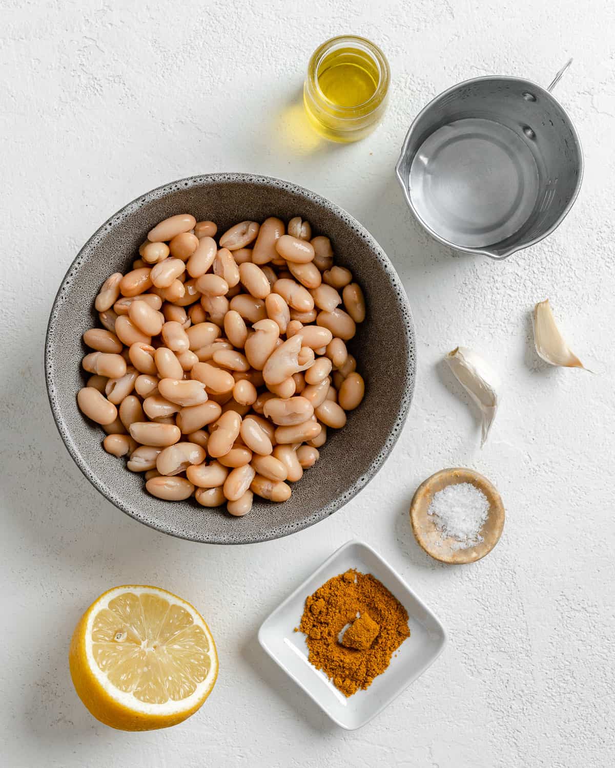 ingredients measured out for curried white bean dip against a white background