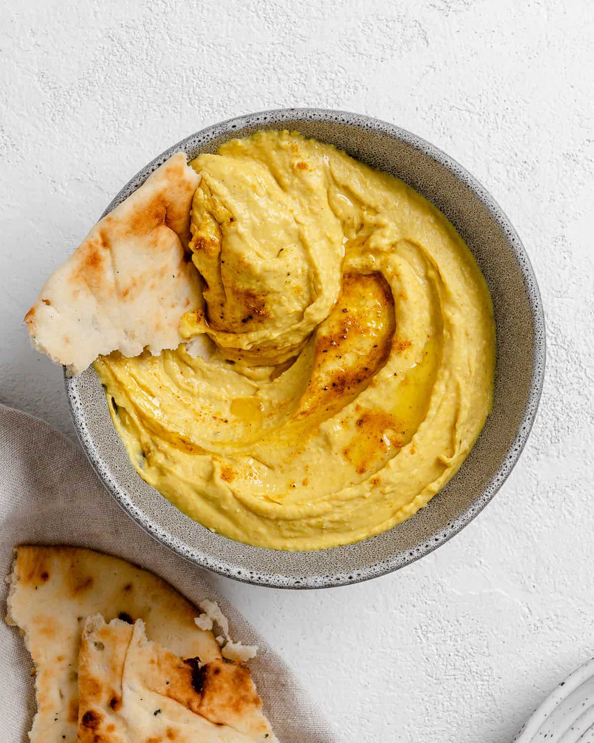 completed Curried White Bean Dip in a gray. bowl against a white background with bread