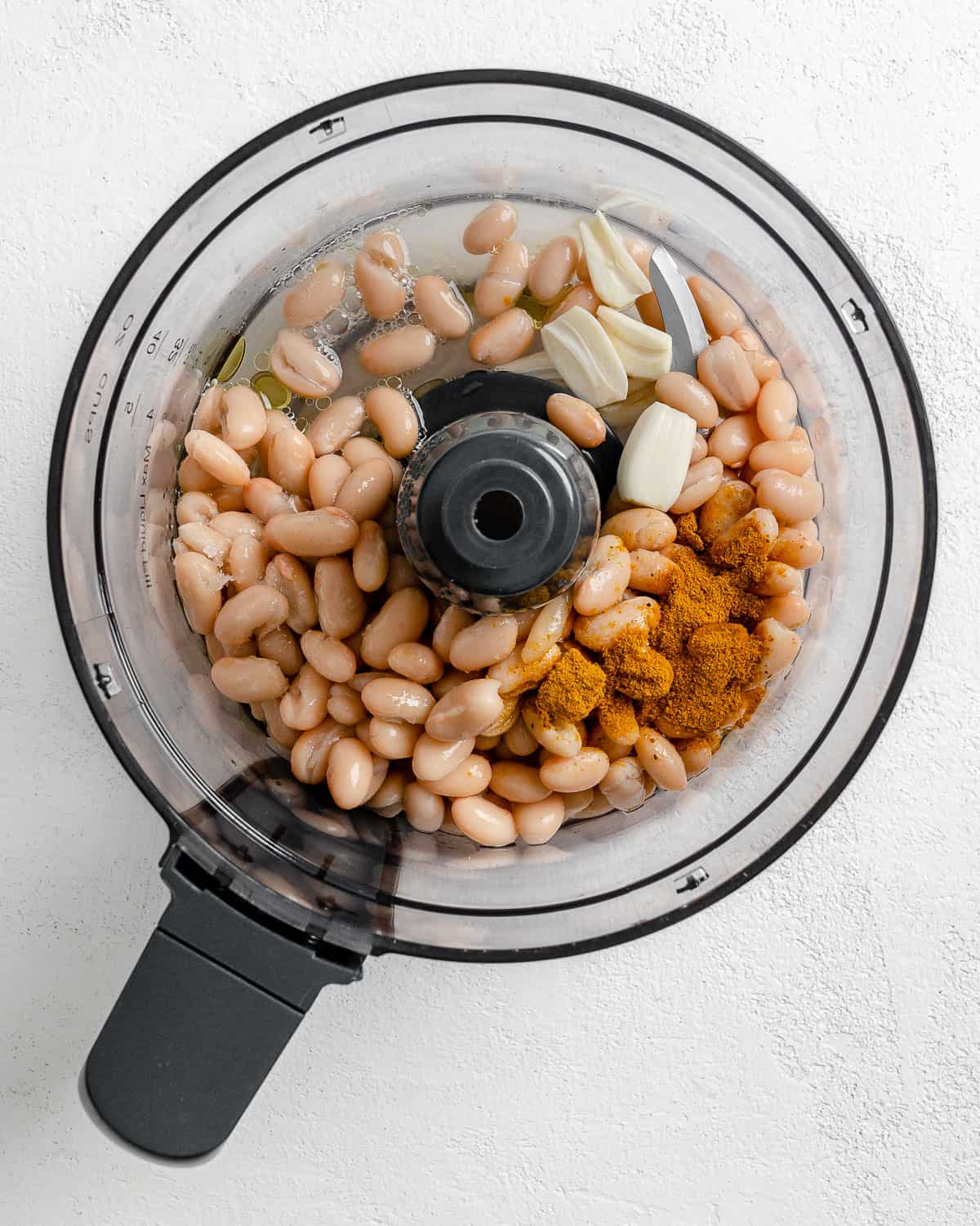 process of adding ingredients into food processor for curried white bean dip