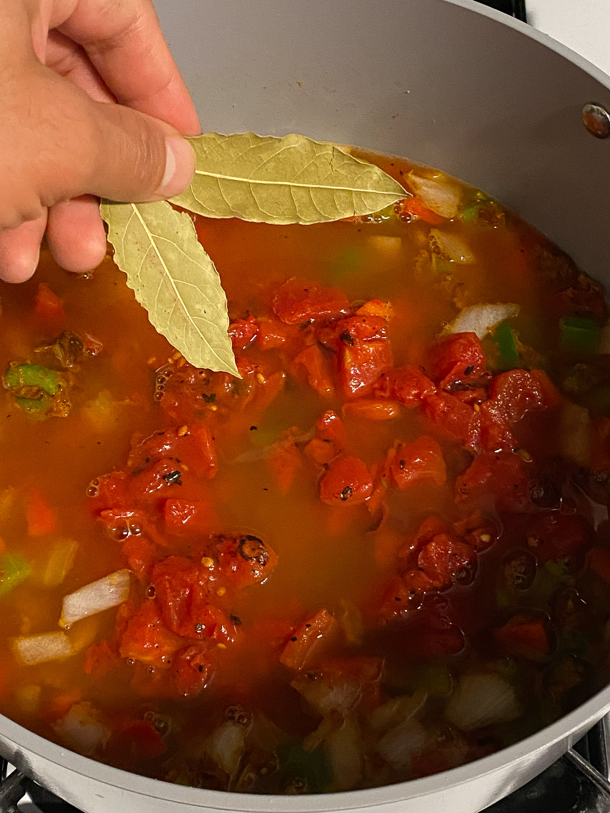 process shot of bay leaves being added to pan