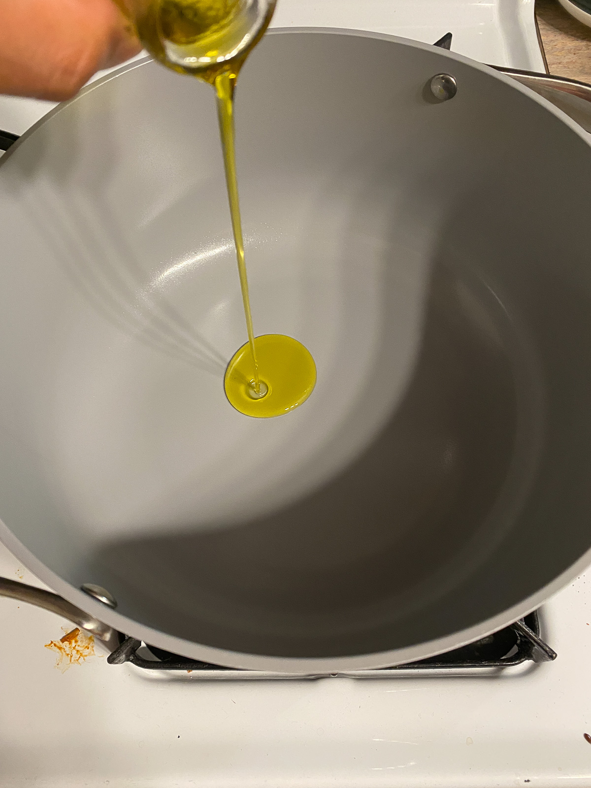 process shot of oil being poured onto a pan