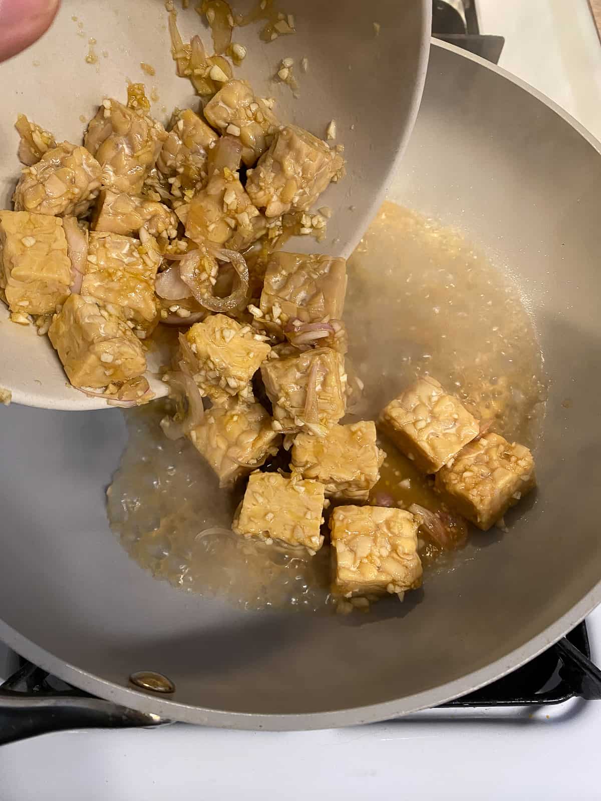 process shot of adding marinated tofu to pan