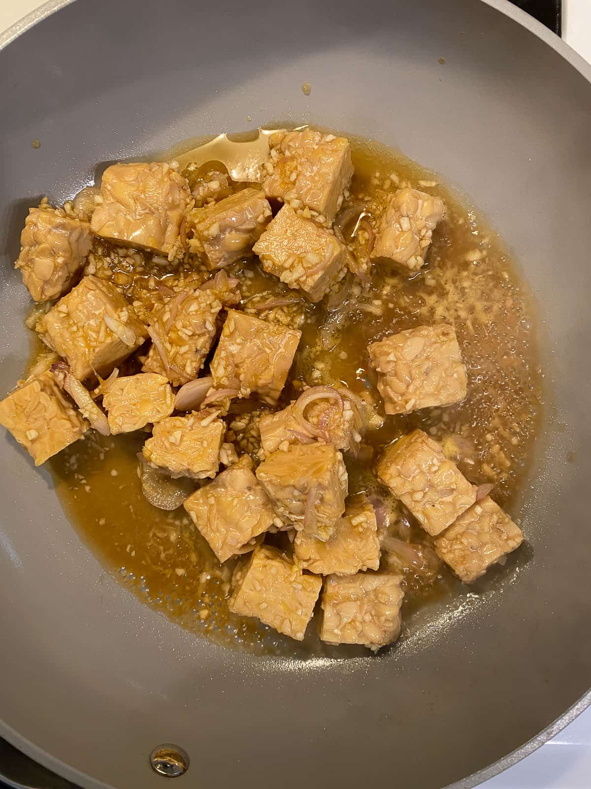 process shot of adding marinated tofu to pan