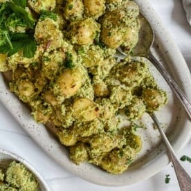completed almond Parsley Potatoes in a white baking dish against a white background