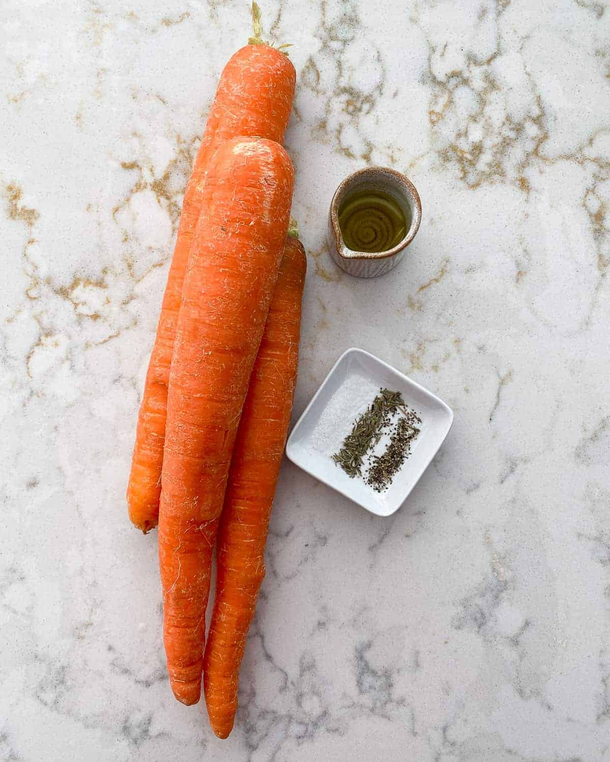 ingredients for carrot fries against a white marble background