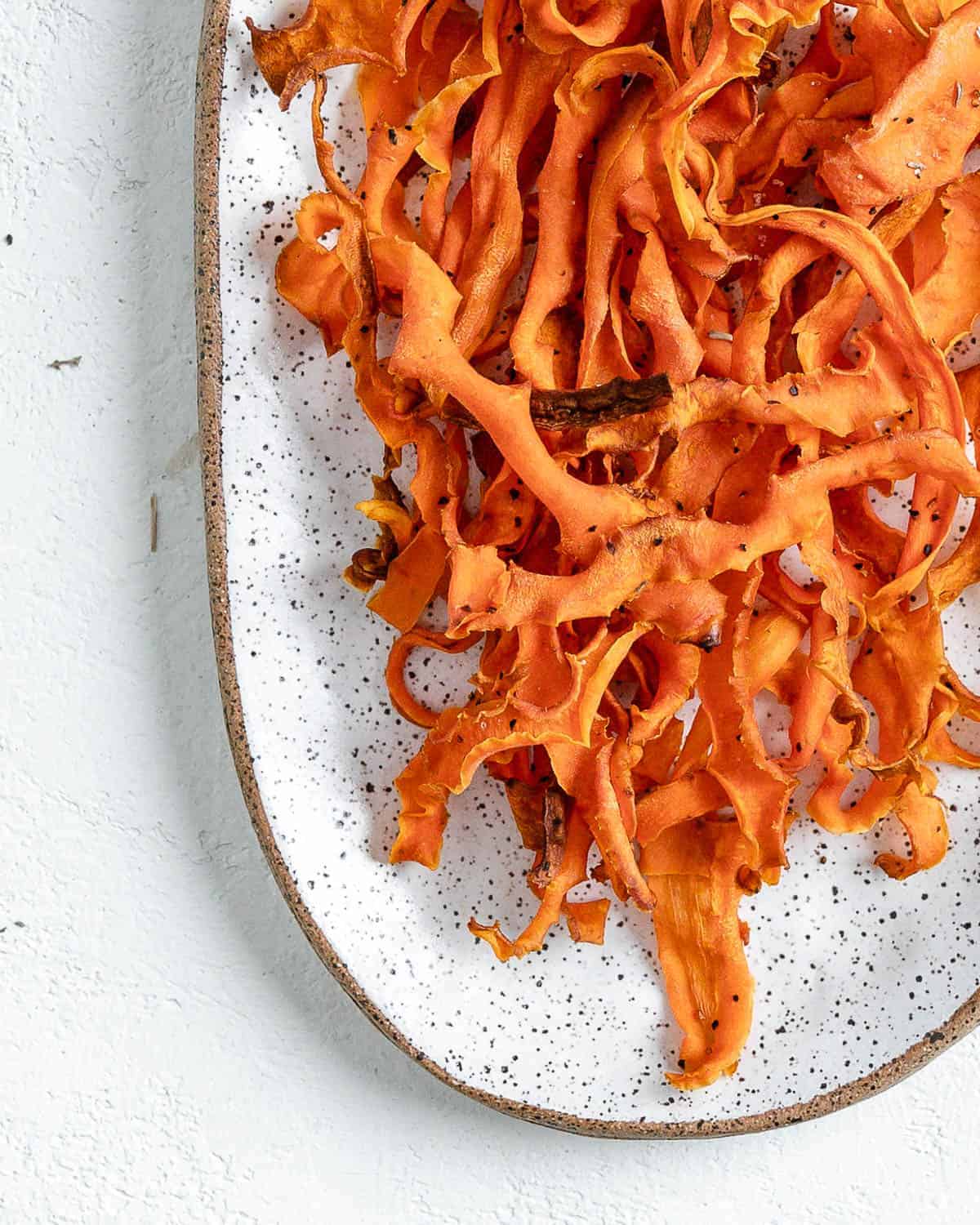 completed carrot fries in a white platter against a white background