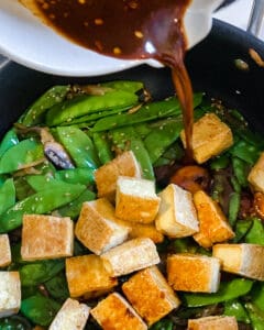 process of adding sauce to tofu and veggies in pan
