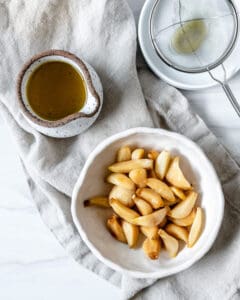 completed Stovetop Roasted Garlic in a white bowl against a white background with oil in the background