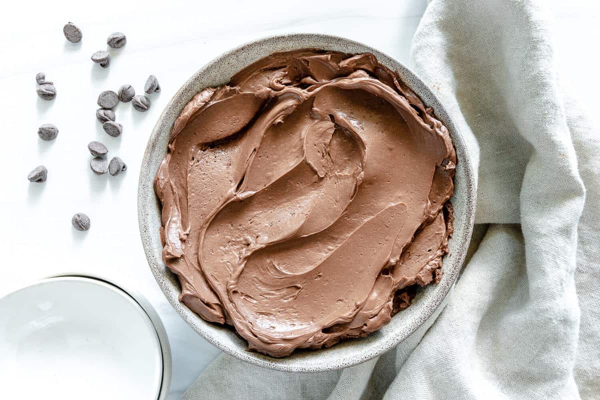 Simple Chocolate Mousse in white bowl in white background with scattered chocoalte chips