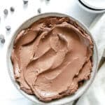 Completed Simple Chocolate Mousse in white bowl in white background with scattered chocolate chips.