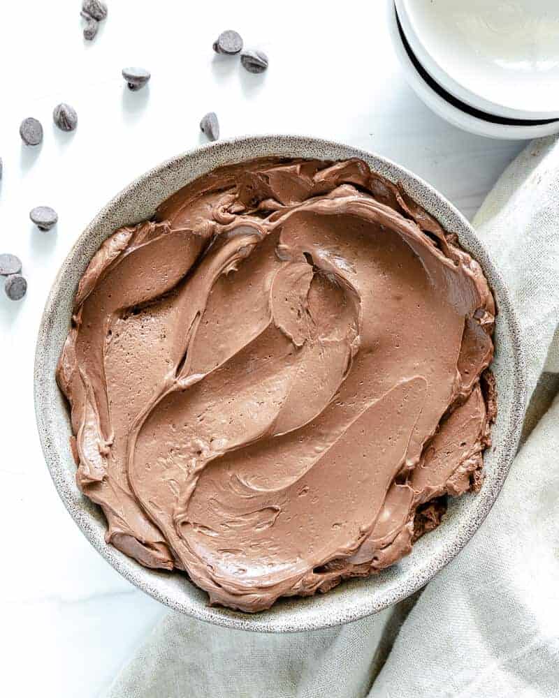 Simple Chocolate Mousse in white bowl in white background with scattered chocoalte chips