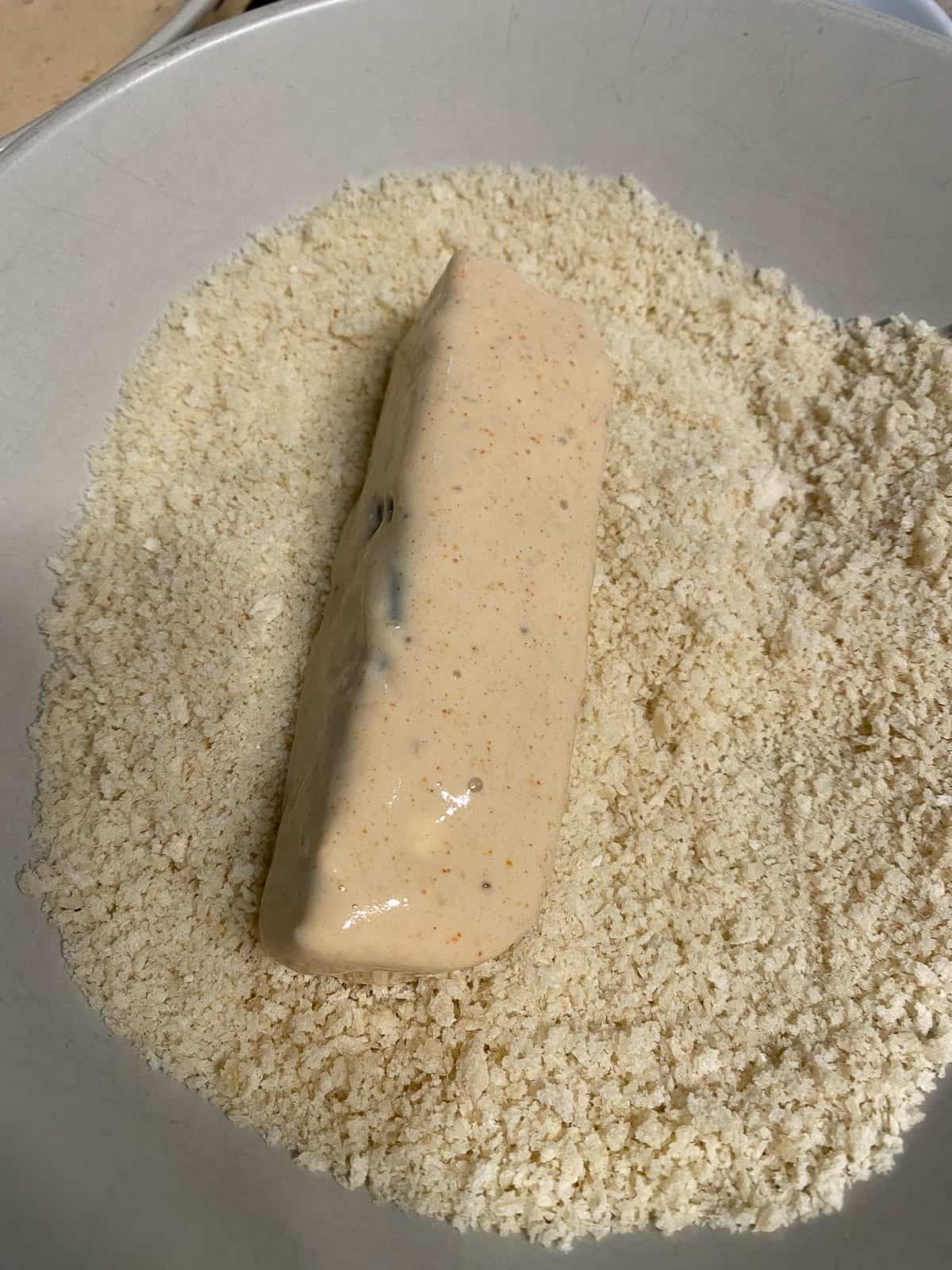process shot of dipping tofu strip into flour mixture