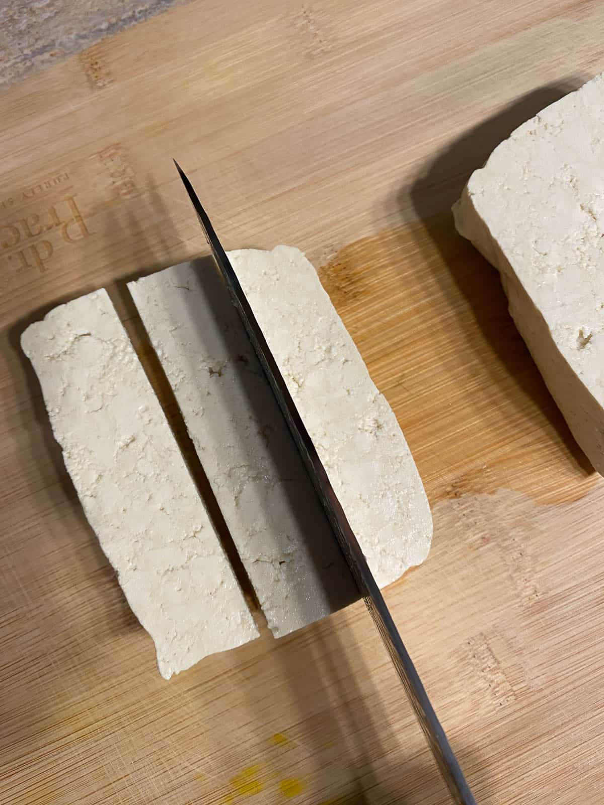 process shot of slicing tofu on cutting board