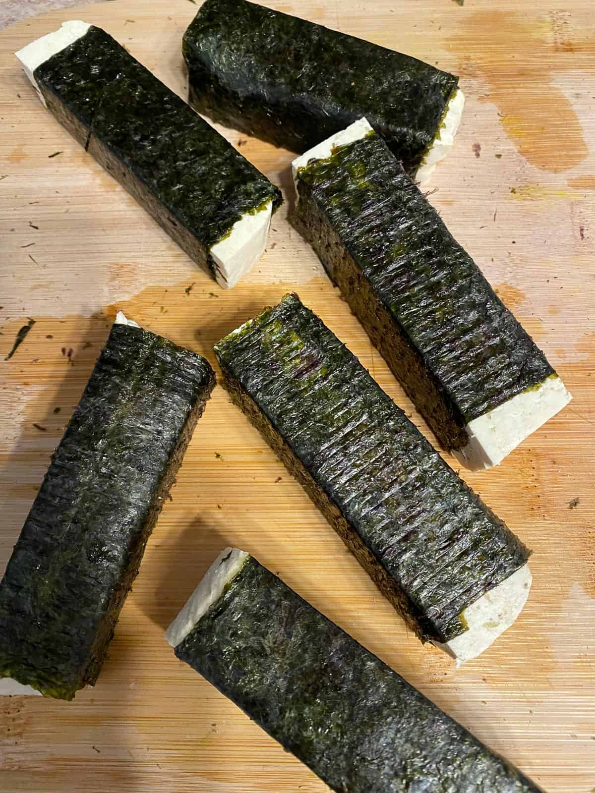 process shot showing several rolled up tofu pieces with nori sheets