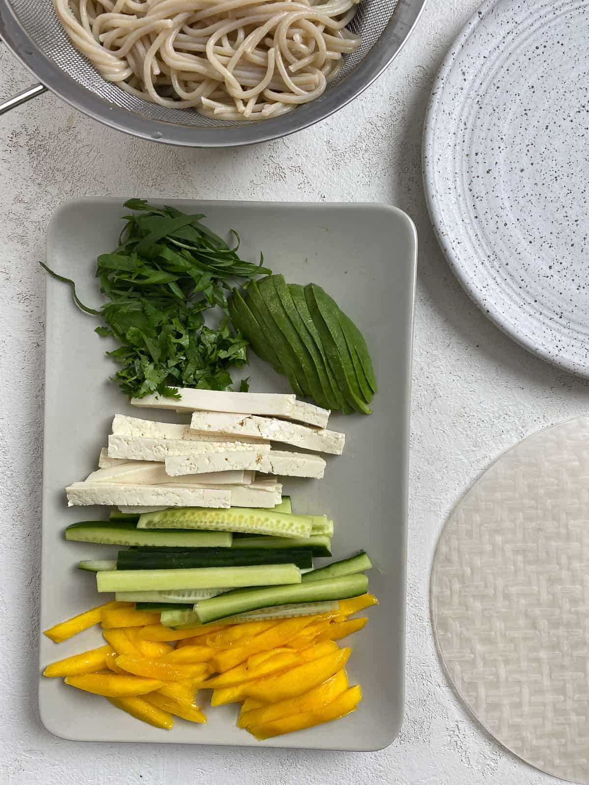 sliced ingredients for Tofu Spring Rolls With Mango and Avocado plated against a light background