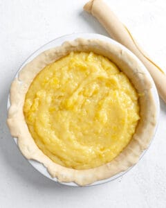 process shot of adding pineapple filling to pie mold against a white background