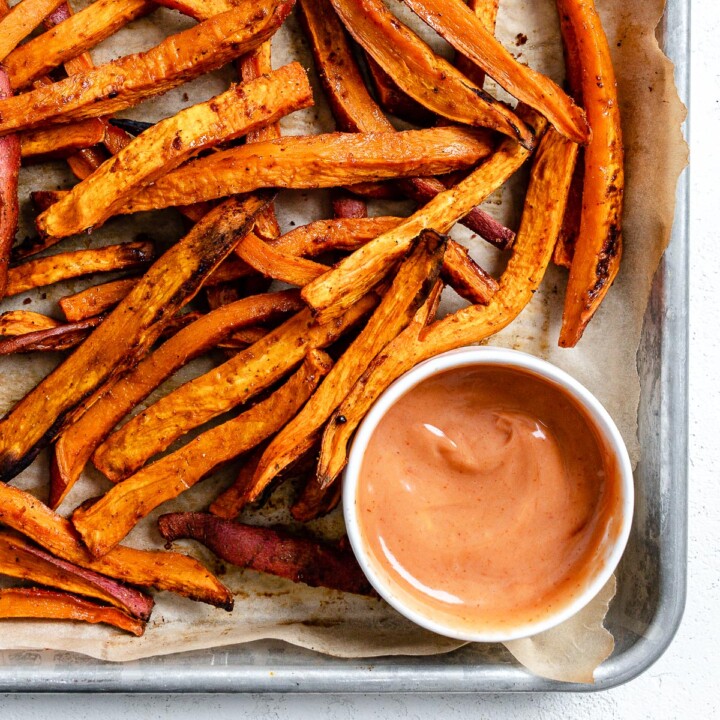 completed sweet potato fries in a baking tray with a small bowl of sauce
