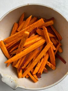 sliced sweet potato with seasonings in a bowl