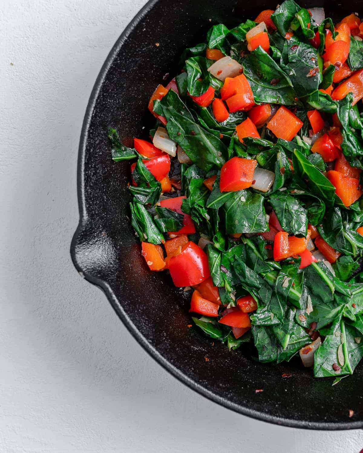 completed Spicy Collard Greens in a black pan against a white surface