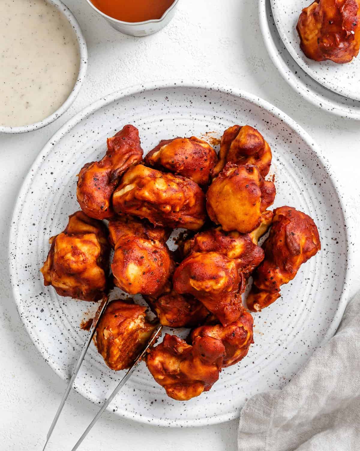 completed BBQ Cauliflower Wings plated on a white plate with a bowl of sauce in the background