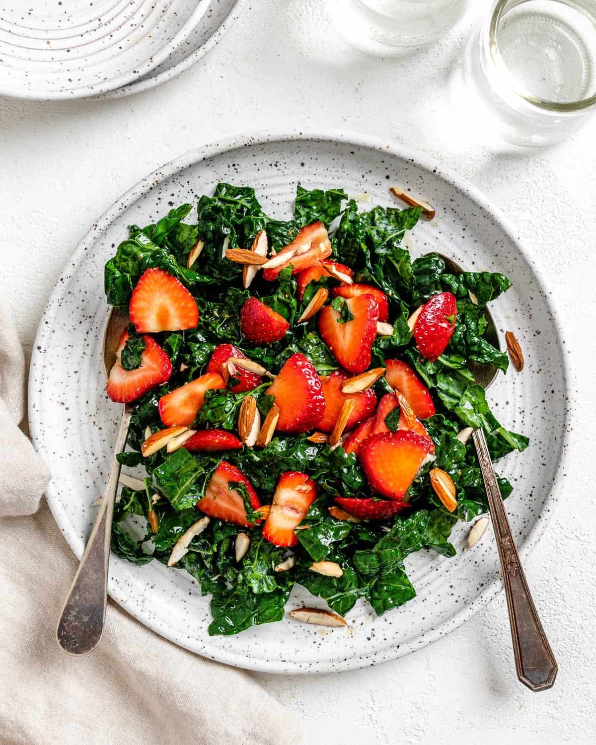 completed Strawberry Kale Salad on a white plate against a white surface