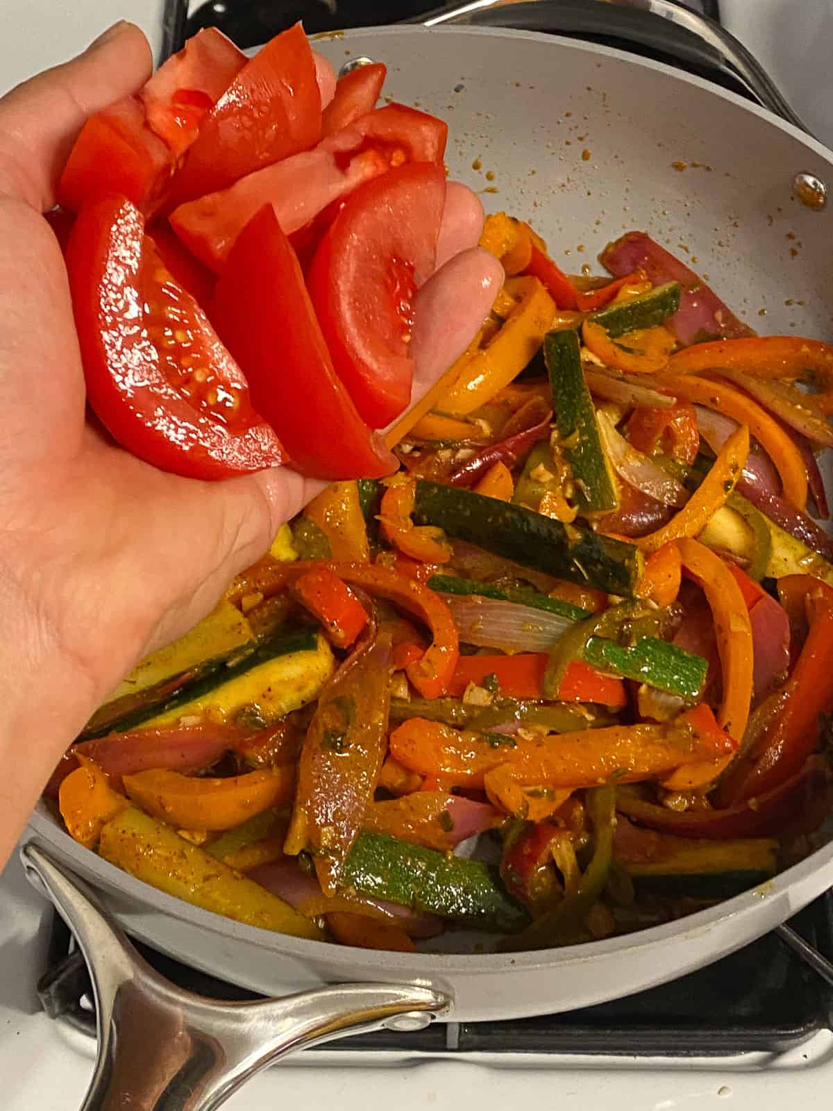 process shot of adding red bell pepper to pan of veggies