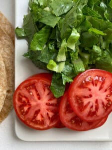 sliced and chopped tomatoes and spinach on a white cutting board