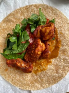 process shot showing addition of cauliflower bites and spinach on wrap