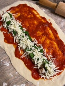 process of adding basil, cheese, and marinara sauce to flour